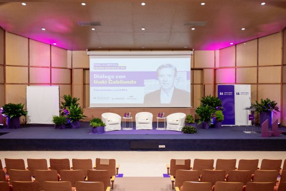 Eventos corporativos Auditorio preparado para un evento, con sillas blancas y pantalla de presentación.