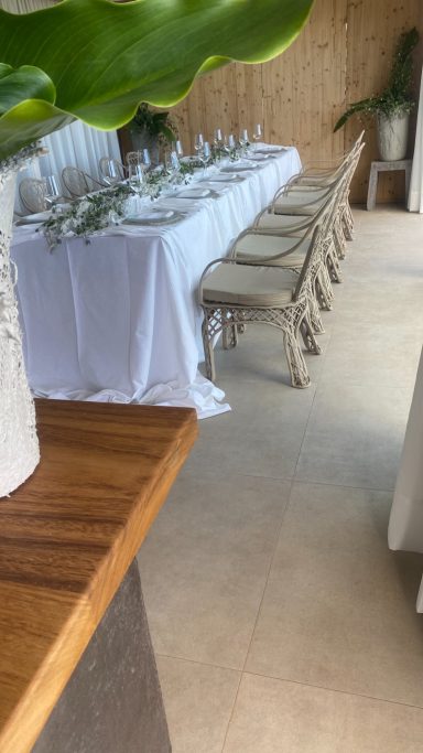Organización de eventos. Celebración privada Mesa con mantel blanco y sillas en un ambiente decorado y luminoso.