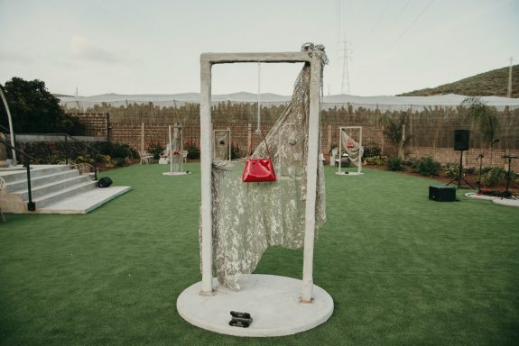 Presentación nueva colección bolsos de diseño Presentación de un bolso rojo decorado con material de construcción en un jardín