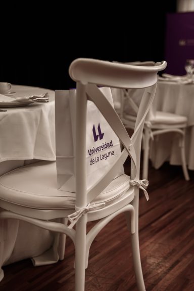 Evento corporativo Silla blanca con un respaldo decorado y mantel en una mesa elegante.