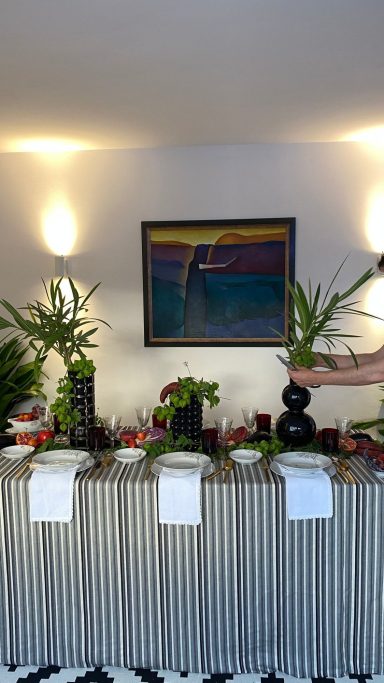 Evento de celebración Mesa decorada con plantas y manteles, con una pintura colorida en la pared de fondo.