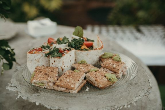 Decoración y catering de eventos Plato con ensalada, tortas de avena y un pastel decorado con verduras y frutas.