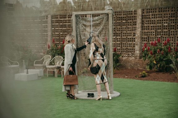 Organización de eventos corporativos Dos personas en un entorno al aire libre interactuando junto a una estructura metálica.