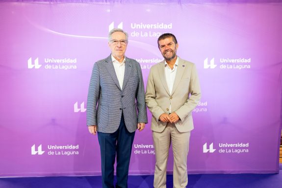 Eventos corporativos Dos hombres sonriendo frente a un fondo morado con el texto de un evento.