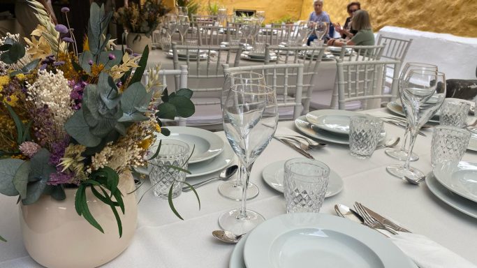 Evento de celebración Mesa elegantemente decorada con flores, platos y copas en un ambiente al aire libre.