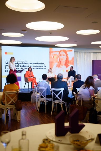 Eventos coporativos Panel de discusión con cuatro ponentes en un evento, público atento en primer plano.